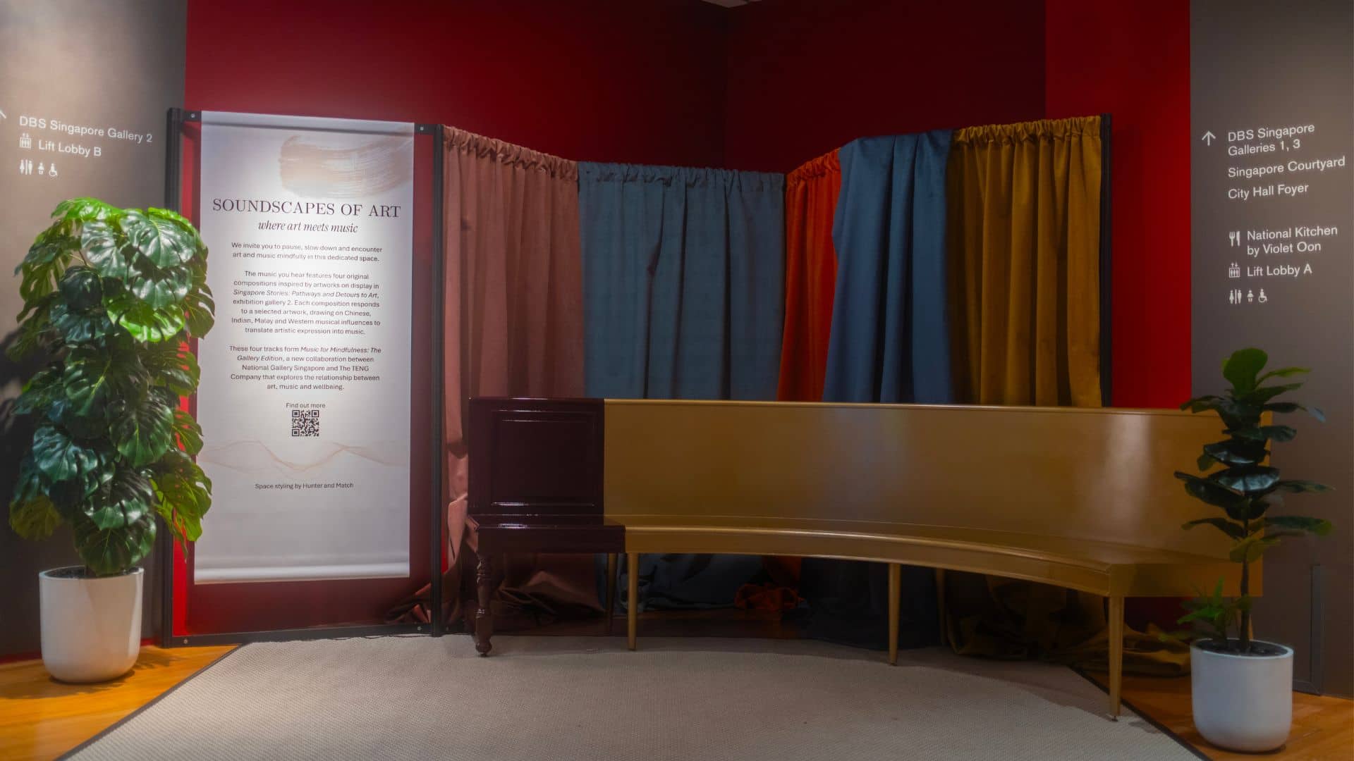 A quiet space with a wooden bench facing a wall-mounted sign that explains the soundscapes of art.