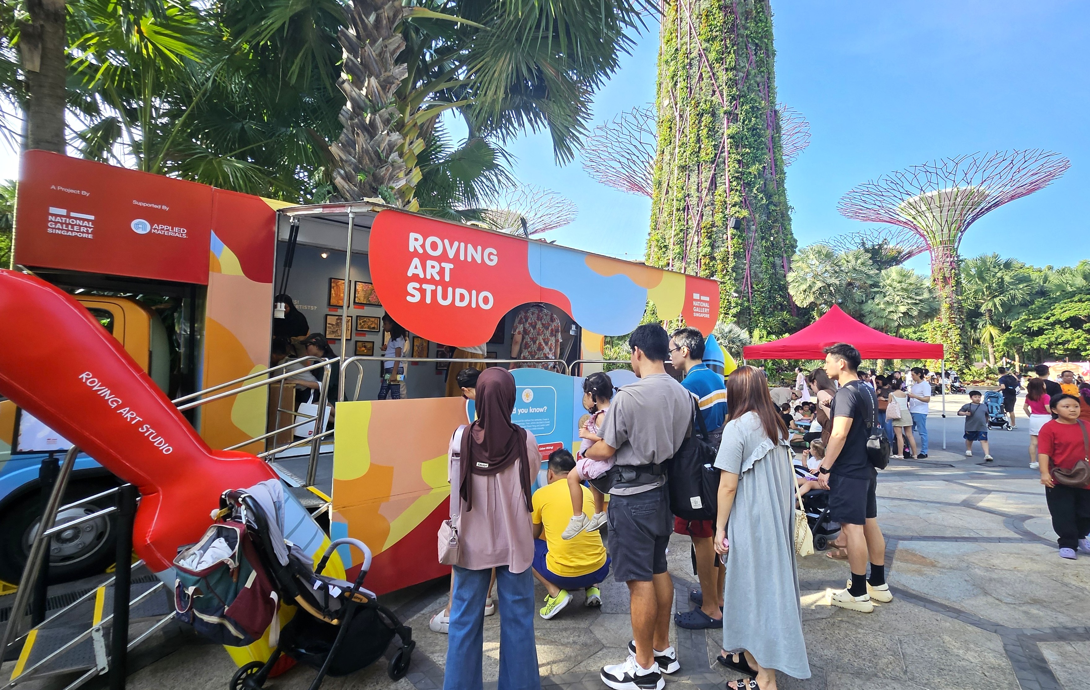 A group of people gathered around a roving art studio truck, engaging in conversation and enjoying art.