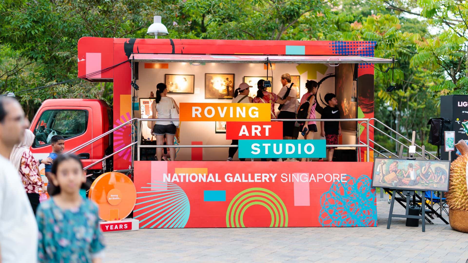 A vibrant mobile art studio in Singapore, where artists are actively creating art in an open-air setting with various tools.