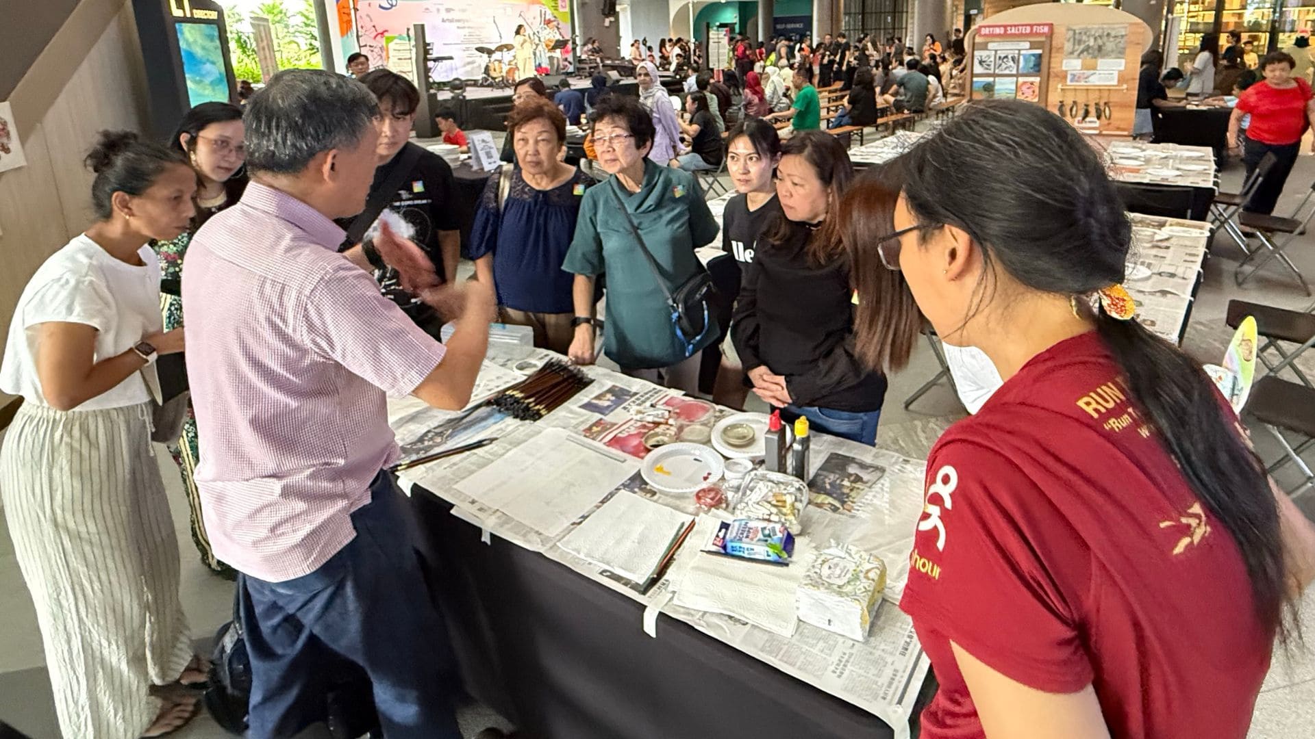 A group of people gathered around a table, engaging with paint and papers during an art workshop.