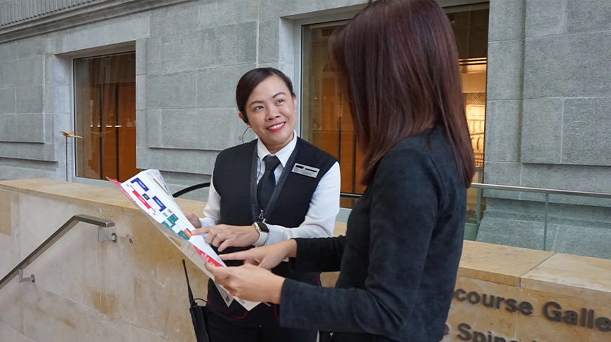 A uniformed security officer interacting with a visitor