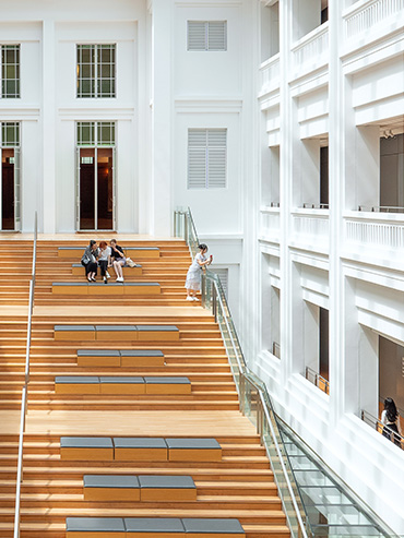Aerial view of visitors lounging at the Singapore Courtyard staircase, with the open space brightly lit by the sun