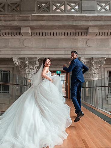 Wedding photoshoot of a bride and a groom turning back as they run across the bridge, smiling at the camera