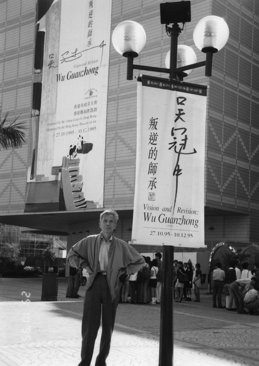 Photograph of Wu Guanzhong before the banner of his exhibition titled "Vision and Revision: Wu Guanzhong"