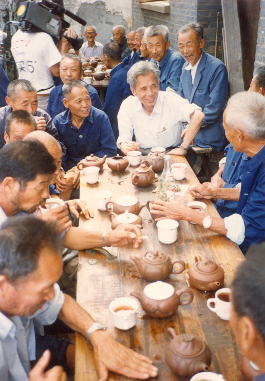 Photograph of Wu Guanzhong in conversation with fellow villagers over tea