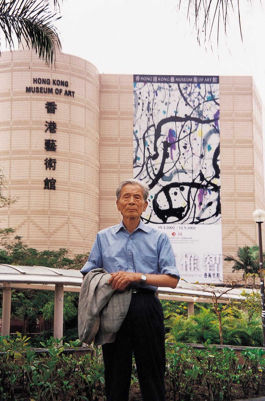 Photograph of Wu Guanzhong before the banner of his exhibition "Wu Guanzhong: A Retrospective"