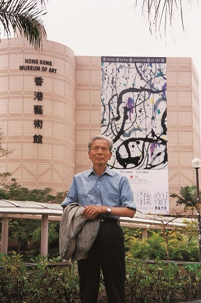 Photograph of Wu Guanzhong before the banner of his exhibition "Wu Guanzhong: A Retrospective"
