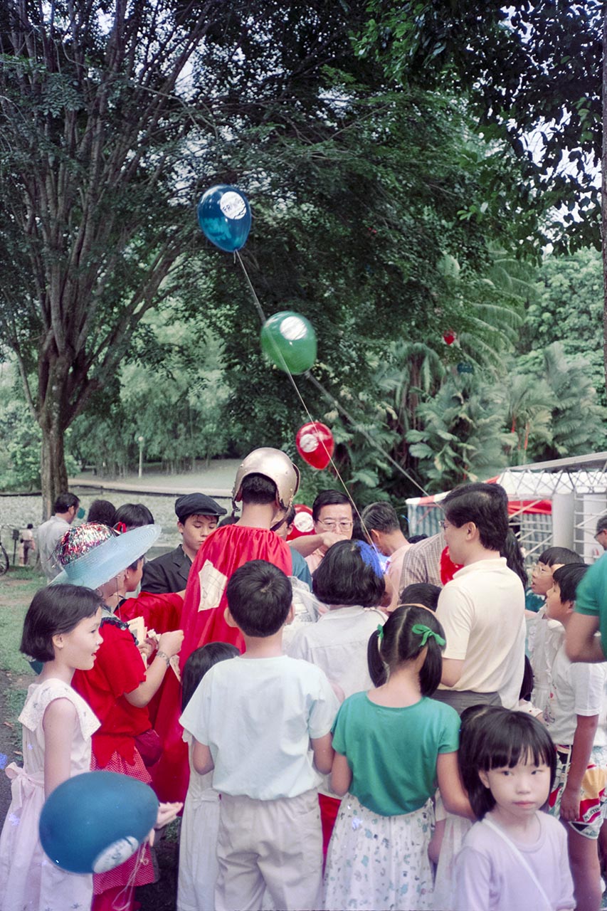 Photographic documentation of a clown distributing balloons at the Singapore Botanic Gardens