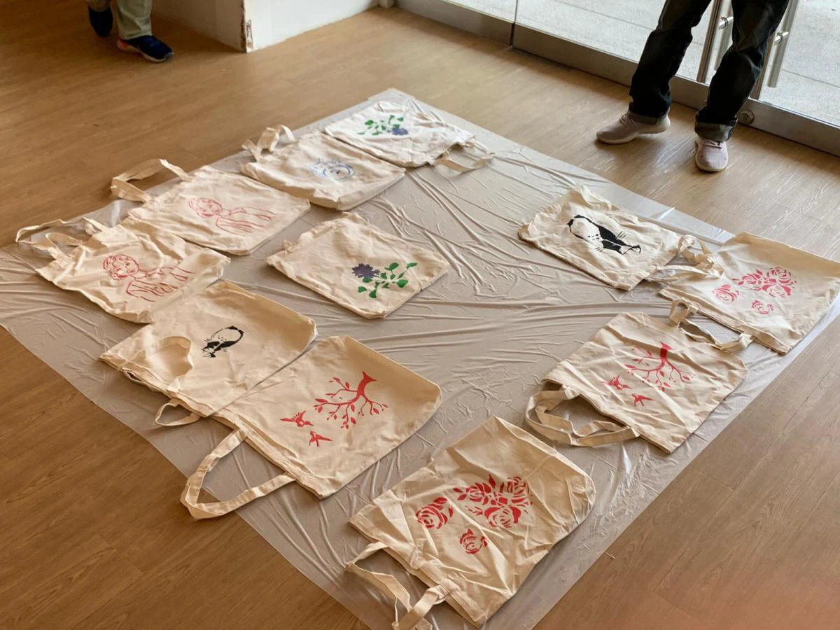 Numerous tote bags drying; each tote bag can be understood as a reflection of the maker’s hopes.