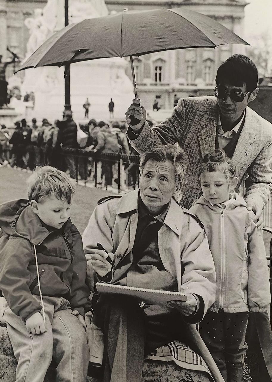Wu Guanzhong Photography Series 吴冠中写真系列
Curious children watch as Wu Guanzhong sketches outdoors, sheltered by his son Wu Keyu. 好奇的孩子在观看吴冠中写生，他的儿子吴可雨在帮其撑伞。