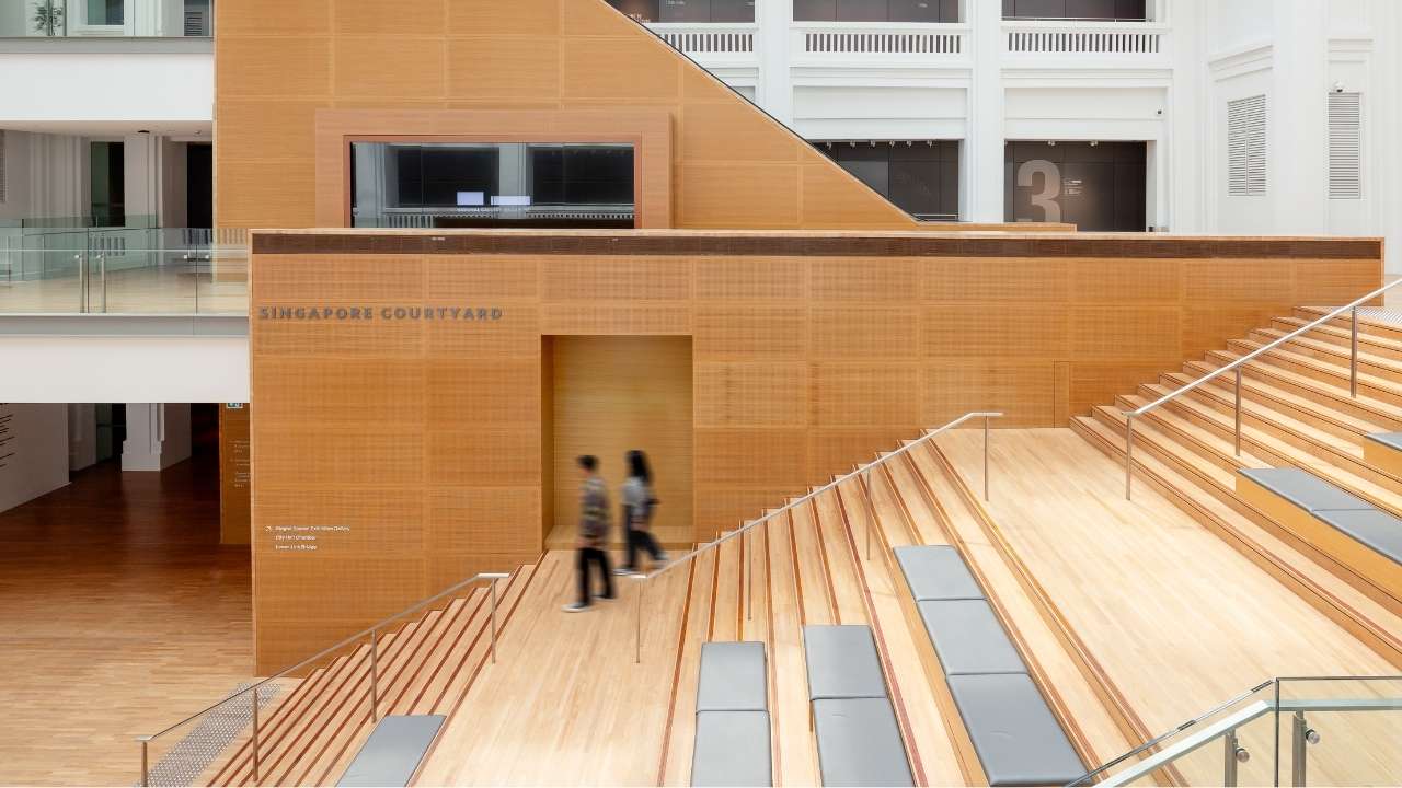 Couple walking together down a grand staircase with sunlit filtering through roof