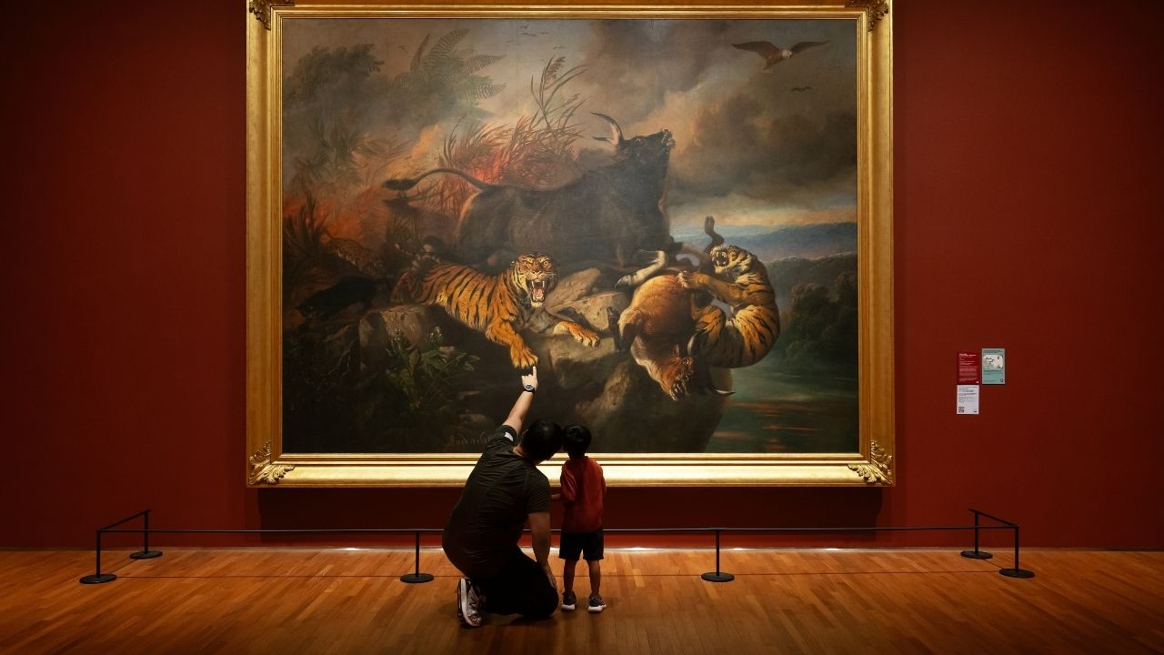 Visitor and child viewing Boschbrand by Raden Saleh on their gallery walk