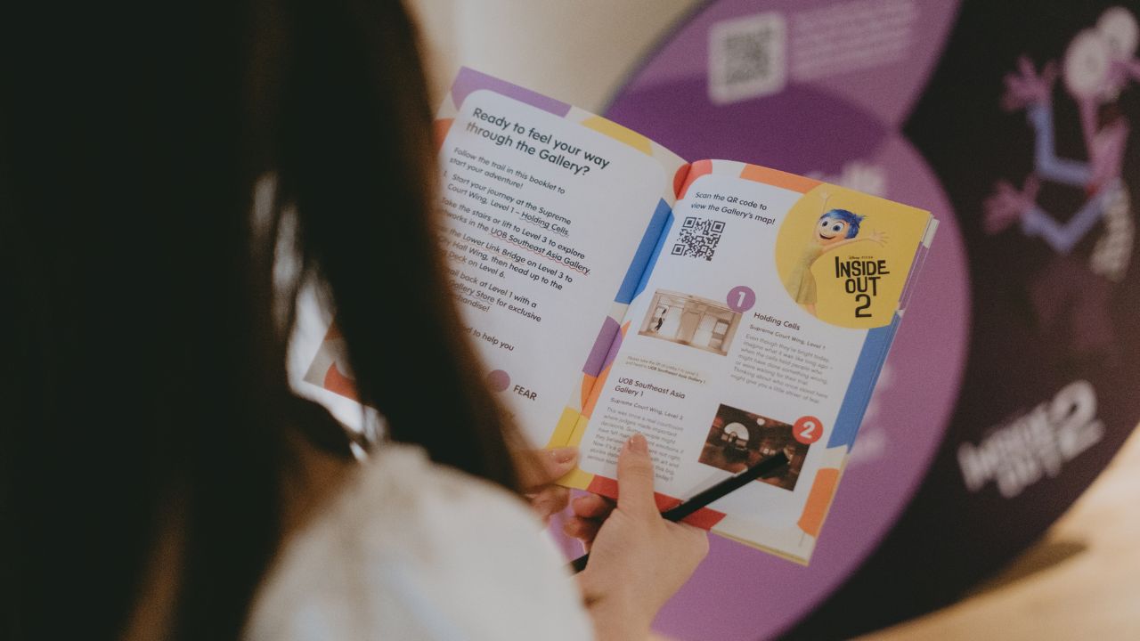 Visitor holding the a colourful Inside Out 2 trail activity booklet