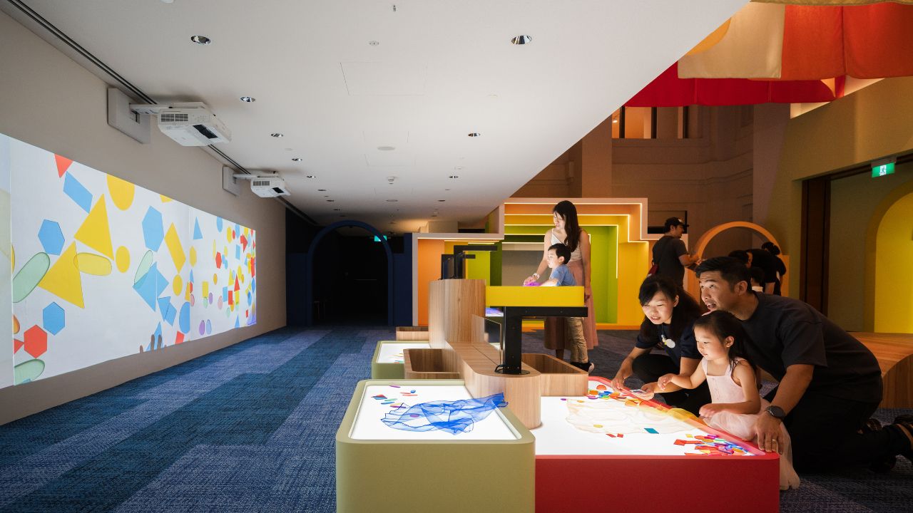 Parents and children playing with colourful pieces to make abstract art and experiment with colours, shapes, light and shadow.