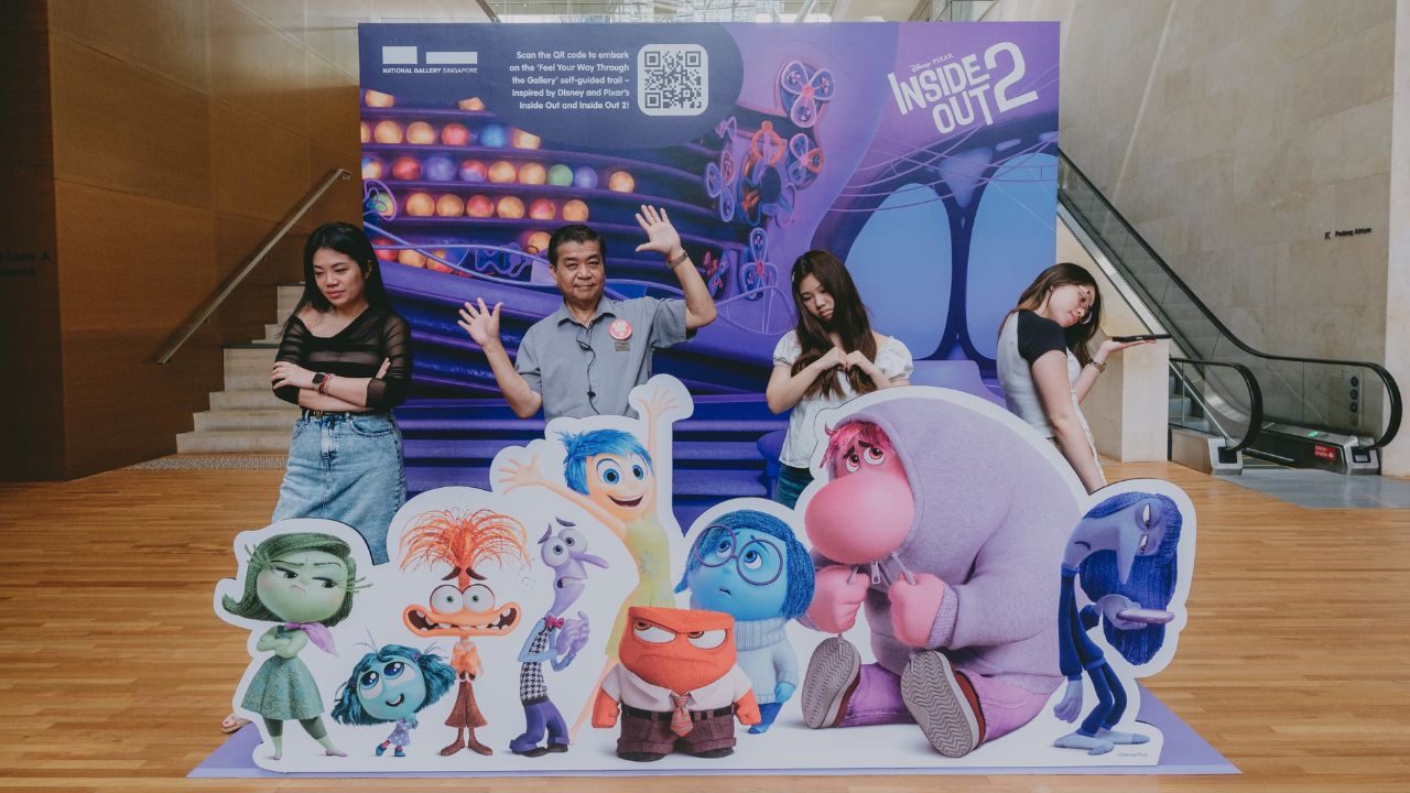 Visitors and a gallery staff taking a group photo at the Inside Out photobooth located inside an art gallery.