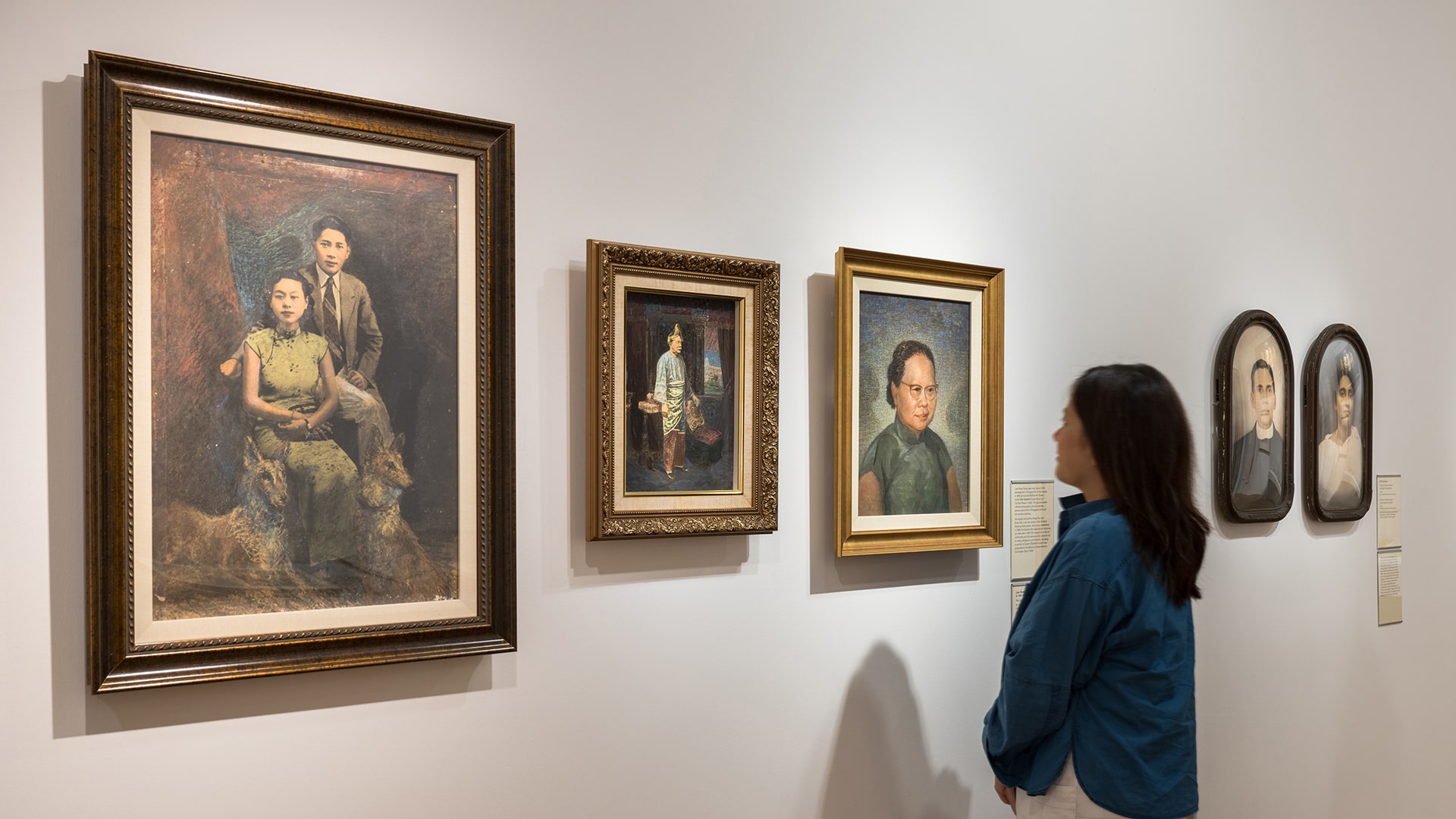 Gallery visitor viewing a collection of artworks on a wall at Singapore Stories, one of the Gallery's permanent exhibitions