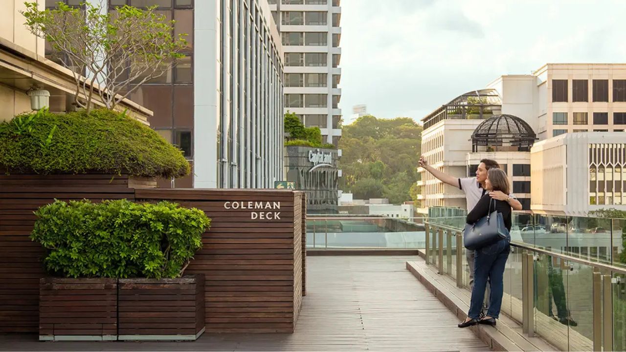 Couple taking photos together on the Coleman Deck, overlooking the Singapore Civic District