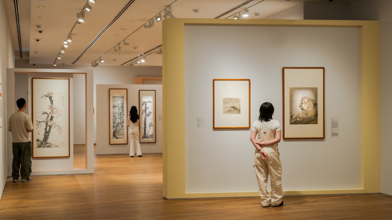 Visitors stand in an art museum, thoughtfully examining a piece of art on display.