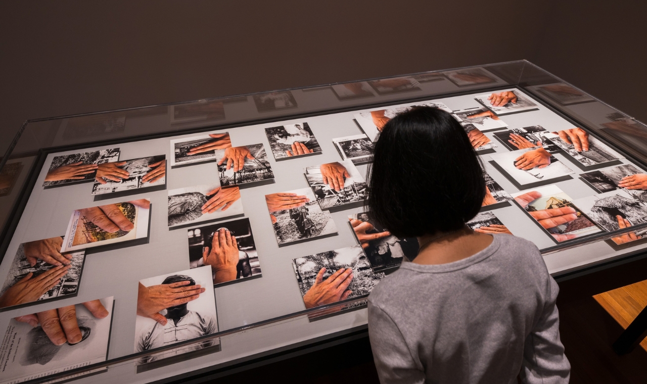 A woman observes photographs displayed in Art Remembers exhibition.