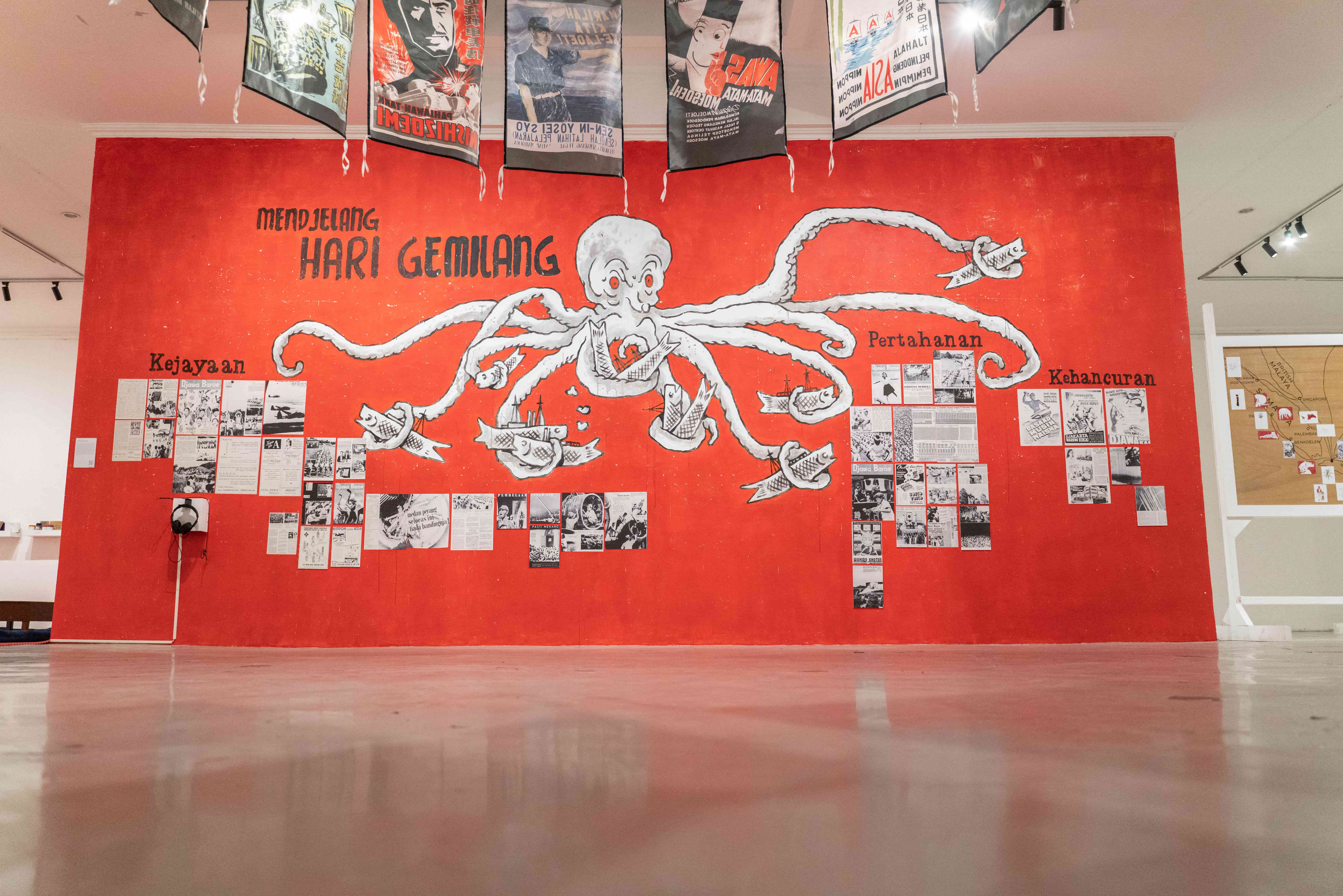 An octopus mural on a red wall, showcasing direct prints and fabric banners in a multimedia exhibition.