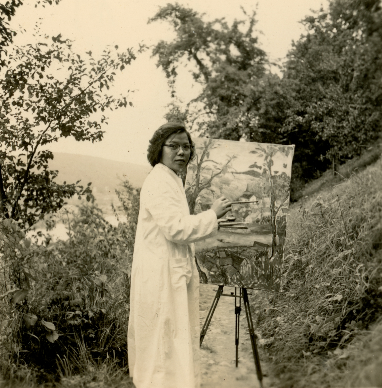 Black and white photo of artist Lai Foong Moi holding her painting in Germany, showcasing her artistic talent and dedication.