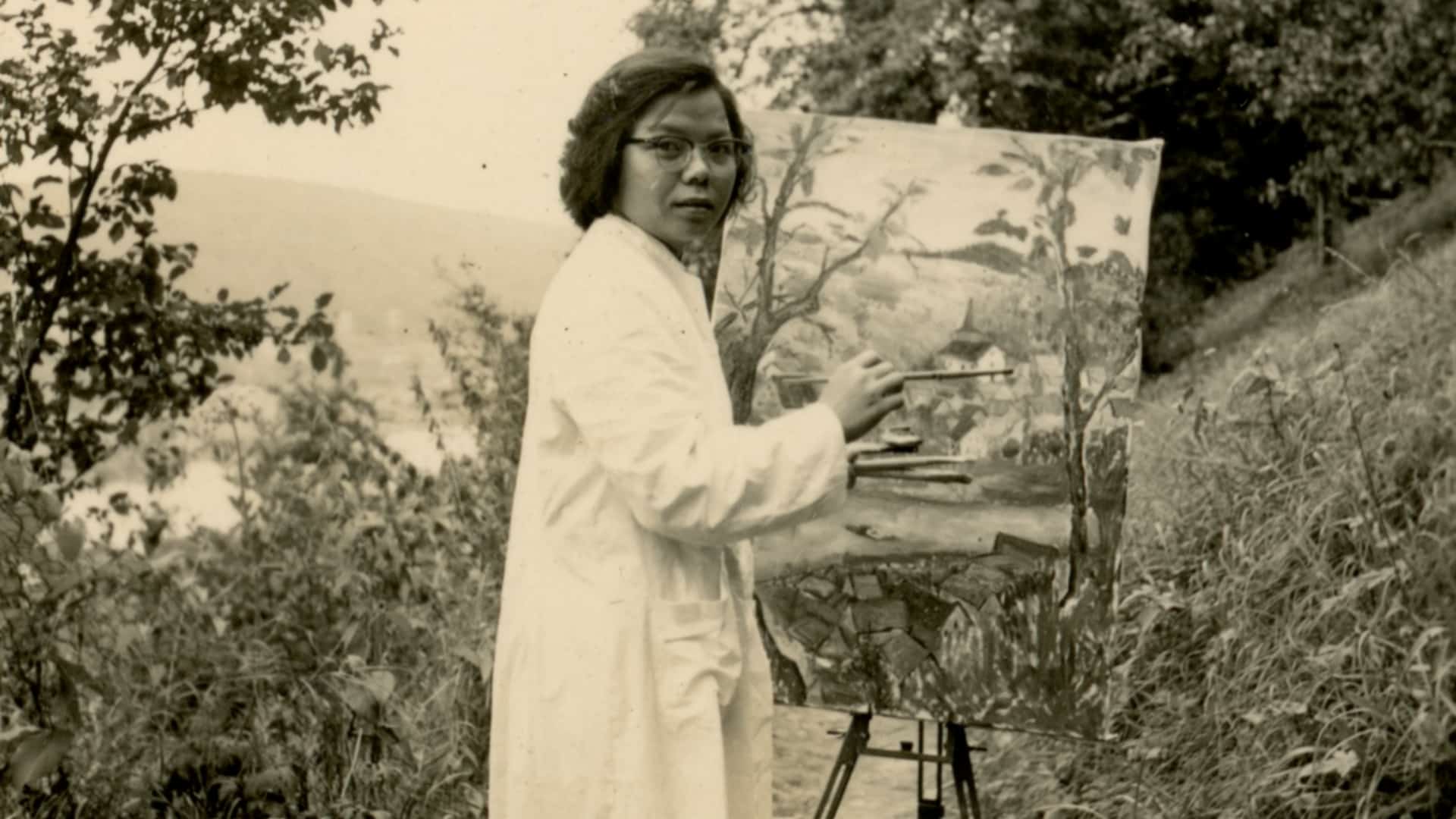 Black and white photo of artist Lai Foong Moi holding her painting in Germany, showcasing her artistic talent and dedication.