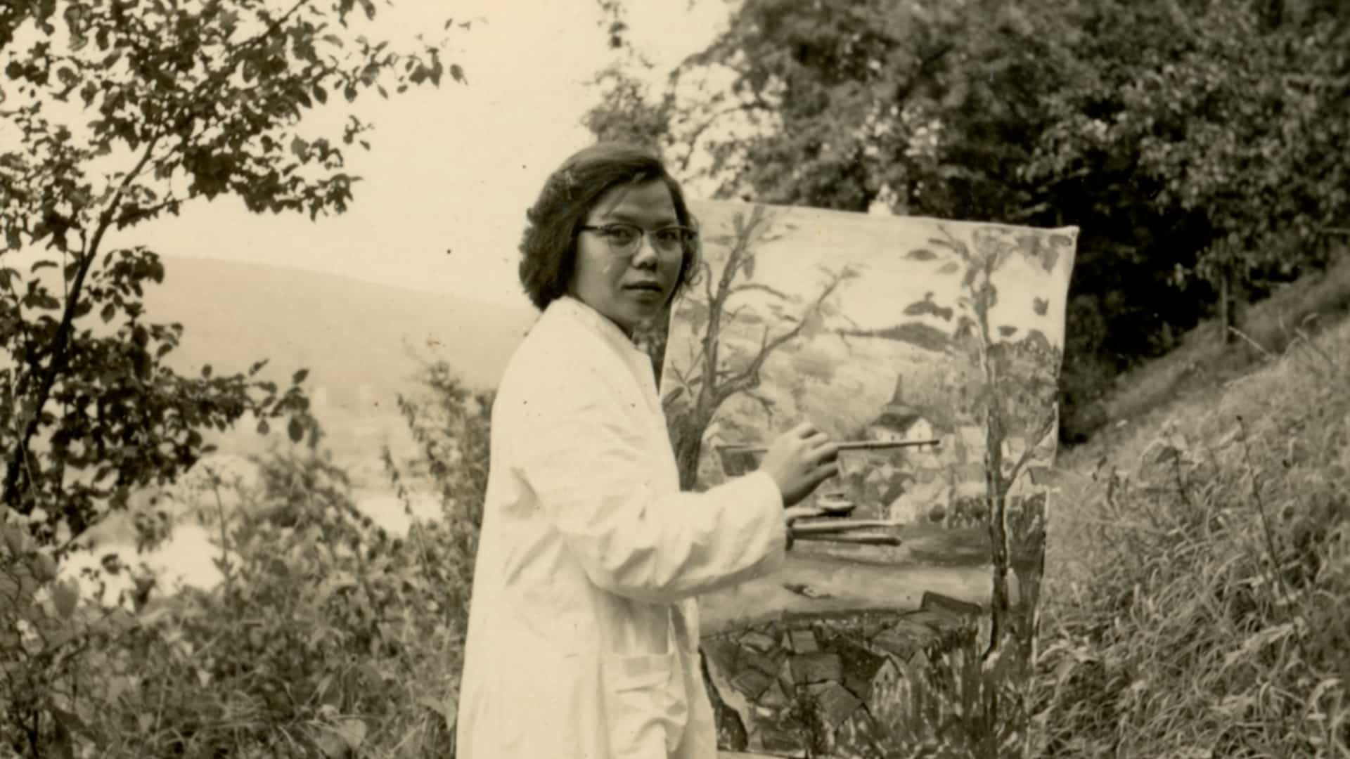 Black and white photo of artist Lai Foong Moi holding her painting in Germany, showcasing her artistic talent and dedication.