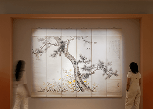 Two women gaze at a tree painting, contemplating its artistic style and the emotions it evokes.