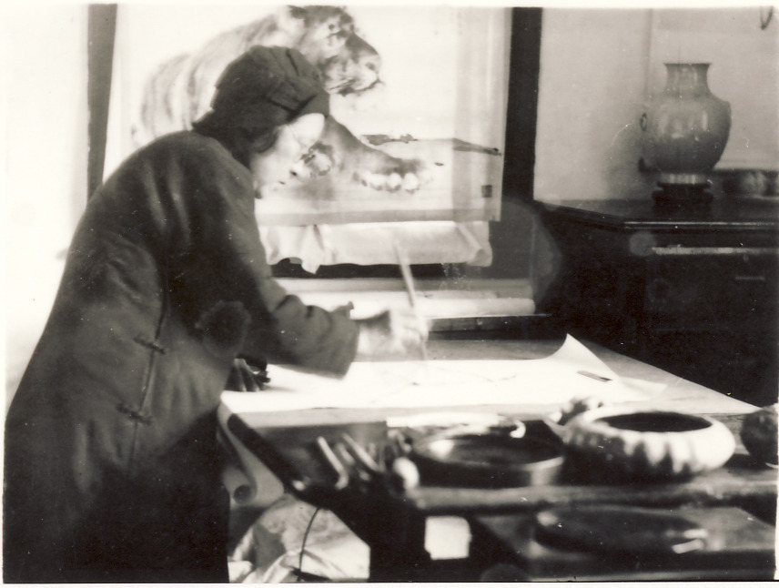 Black and white photograph of He Xiangning, a Chinese artist, standing over a table with her painting for a charity exhibition in 1931