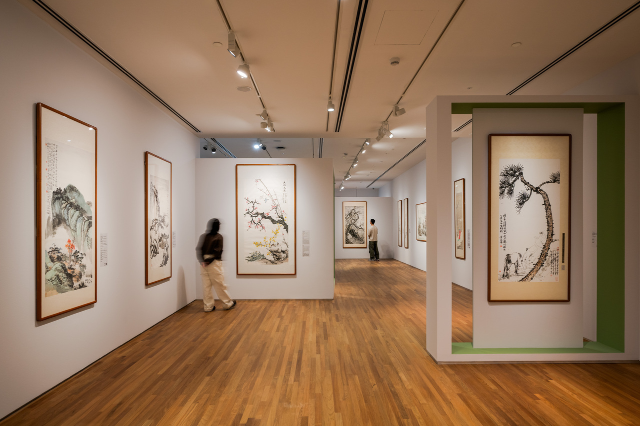 A woman gazes at a painting in an art gallery, surrounded by various Chinese ink artworks and a serene ambiance.