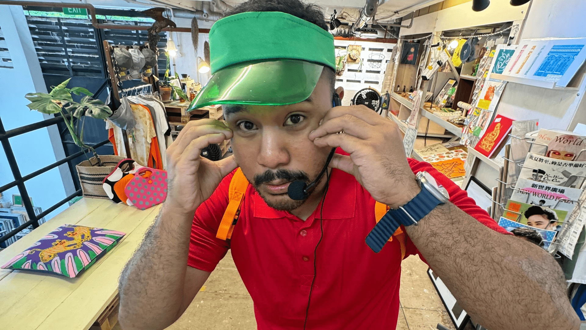 Close up image of Singaporean personality and content creator, Zaki Hussain, wearing a red shirt and green visor.