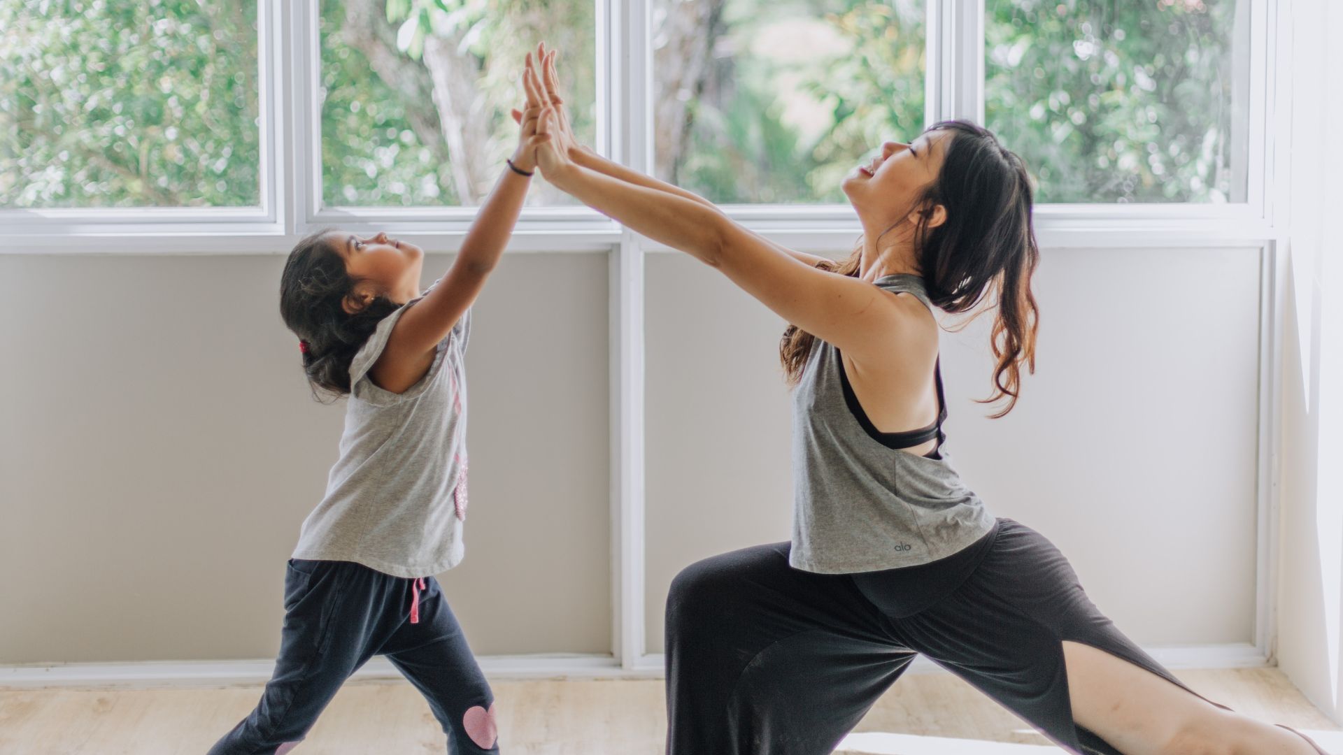 A woman and a young girl practicing yoga together on mats, demonstrating a shared moment of mindfulness and exercise.