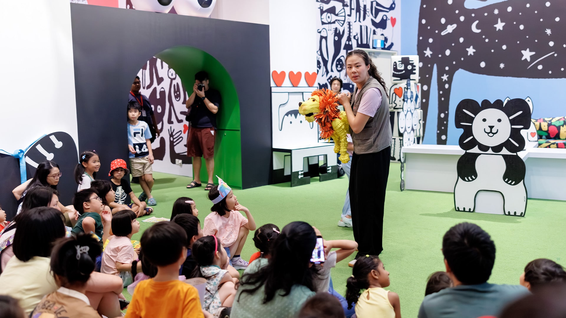 Image of a group of parents and children watching a performance inside a colourful art gallery