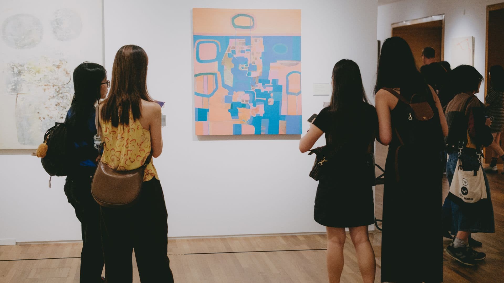 Visitors observe various artworks displayed in a spacious art museum gallery.