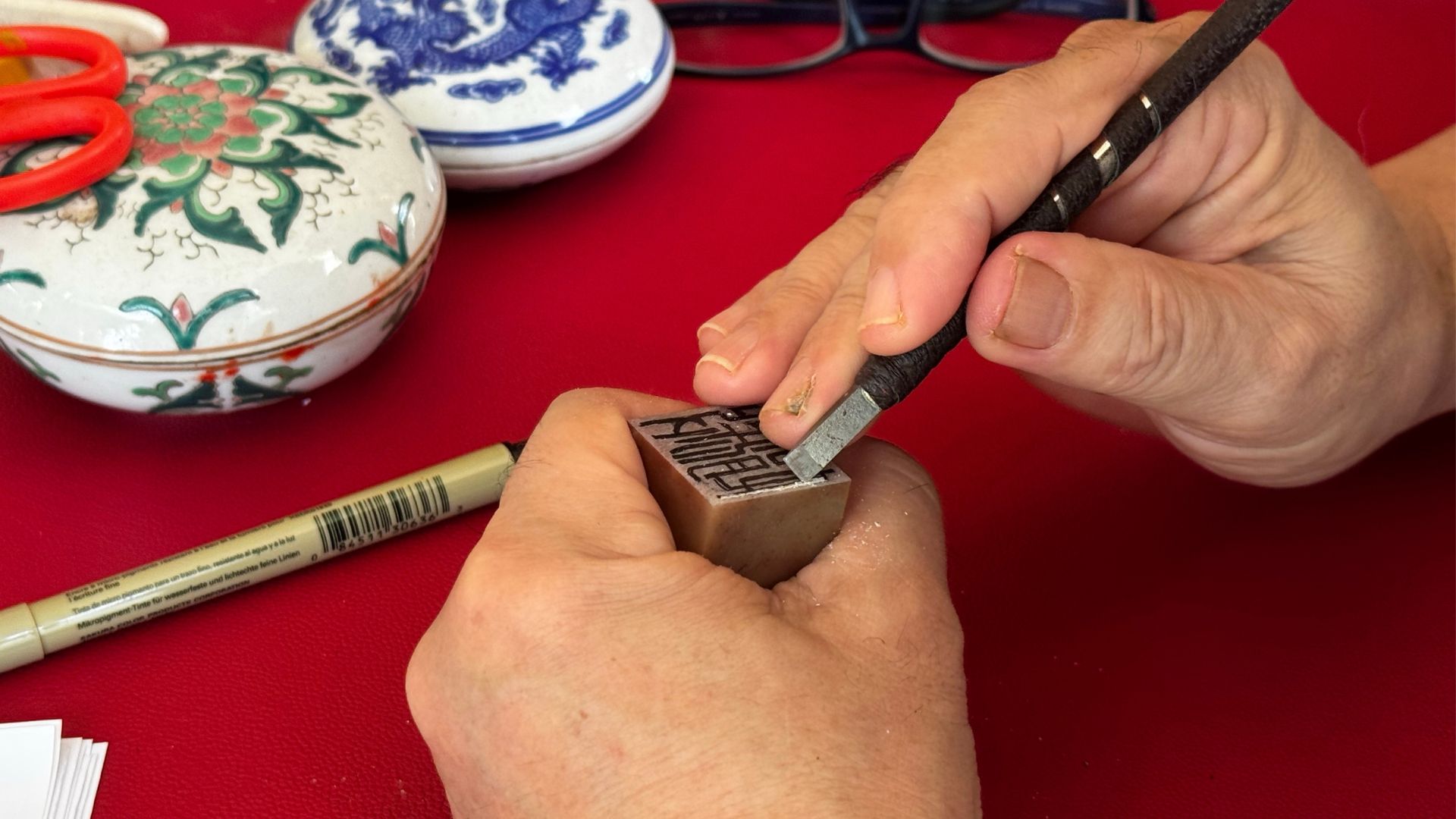 Craftsman carving Chinese characters into a wooden block to create a seal